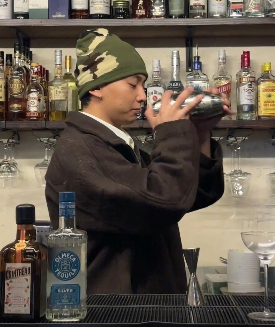 Un bartender agitando vigorosamente una coctelera para enfriar los ingredientes.