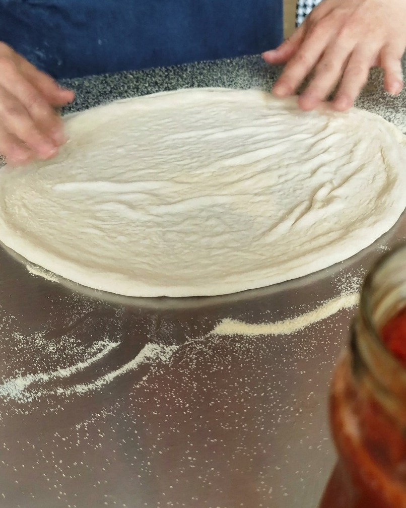 Masa de pizza extendida sobre una superficie espolvoreada con sémola.