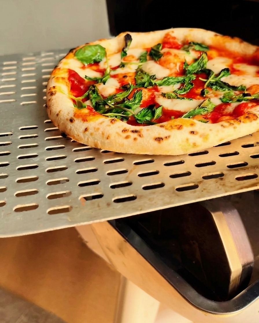 Pizza Margherita recién salida del horno con corteza charred.