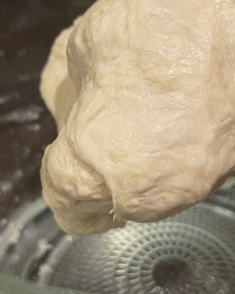 Una bola de masa suave y elástica amasada a mano, lista para la fermentación.