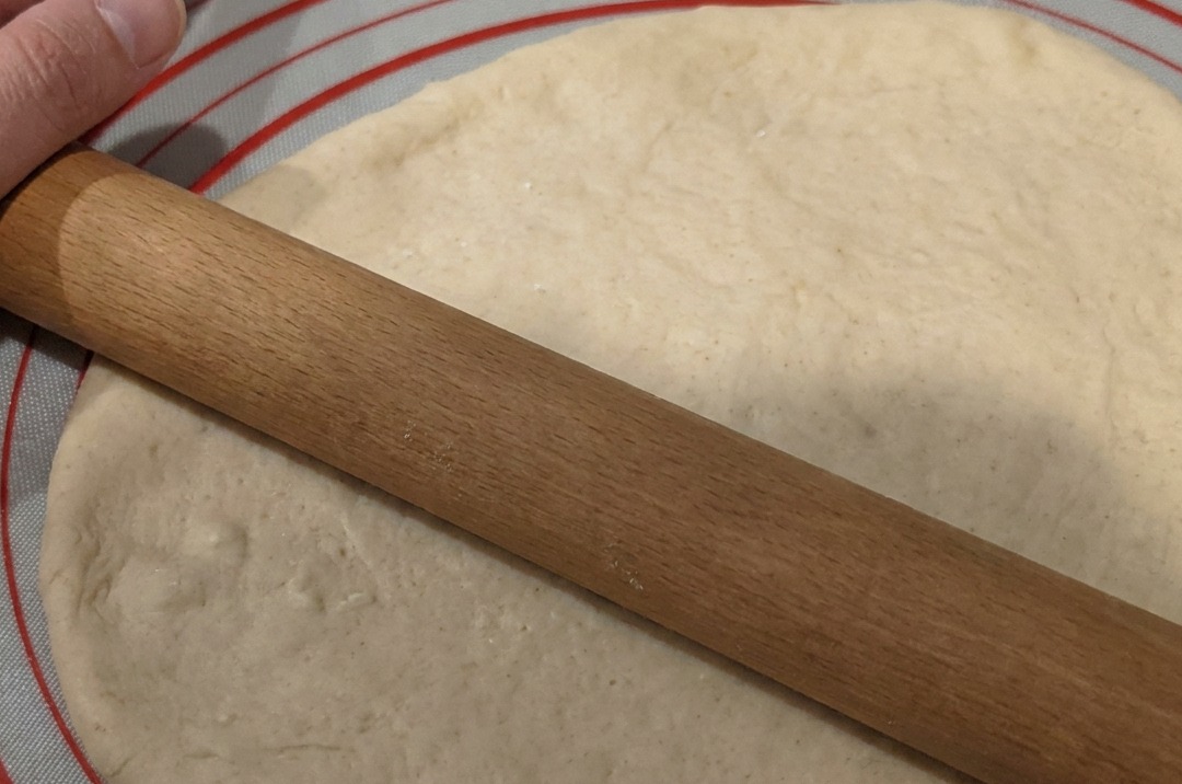 Masa siendo estirada en un círculo plano sobre una esterilla de silicona antiadherente.