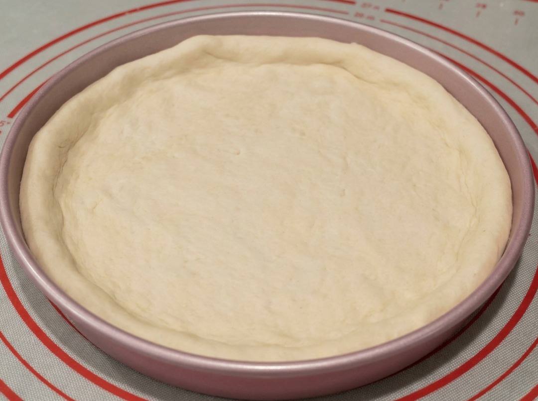 Masa colocada en un molde metálico de pizza de 9 pulgadas con los bordes formados a mano.