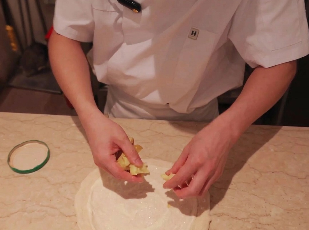 Láminas de papa dispuestas sobre una base de pizza con salsa.