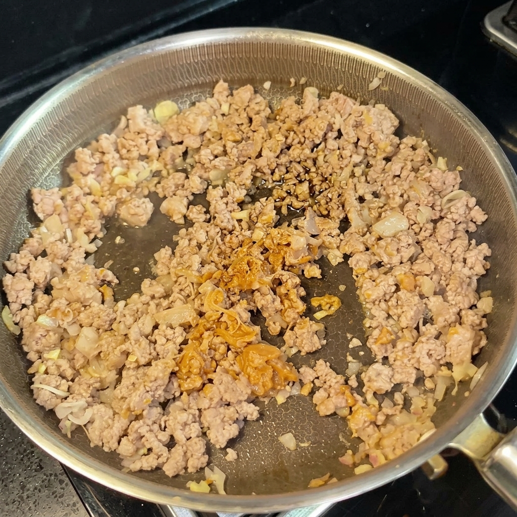 Leche de soja y salsa de soja siendo añadidas a la sartén para formar una salsa cremosa.