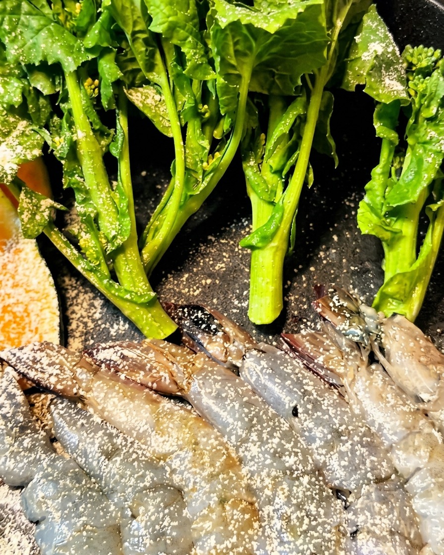 Camarones y berenjena siendo cubiertos en masa y colocados en la freidora.