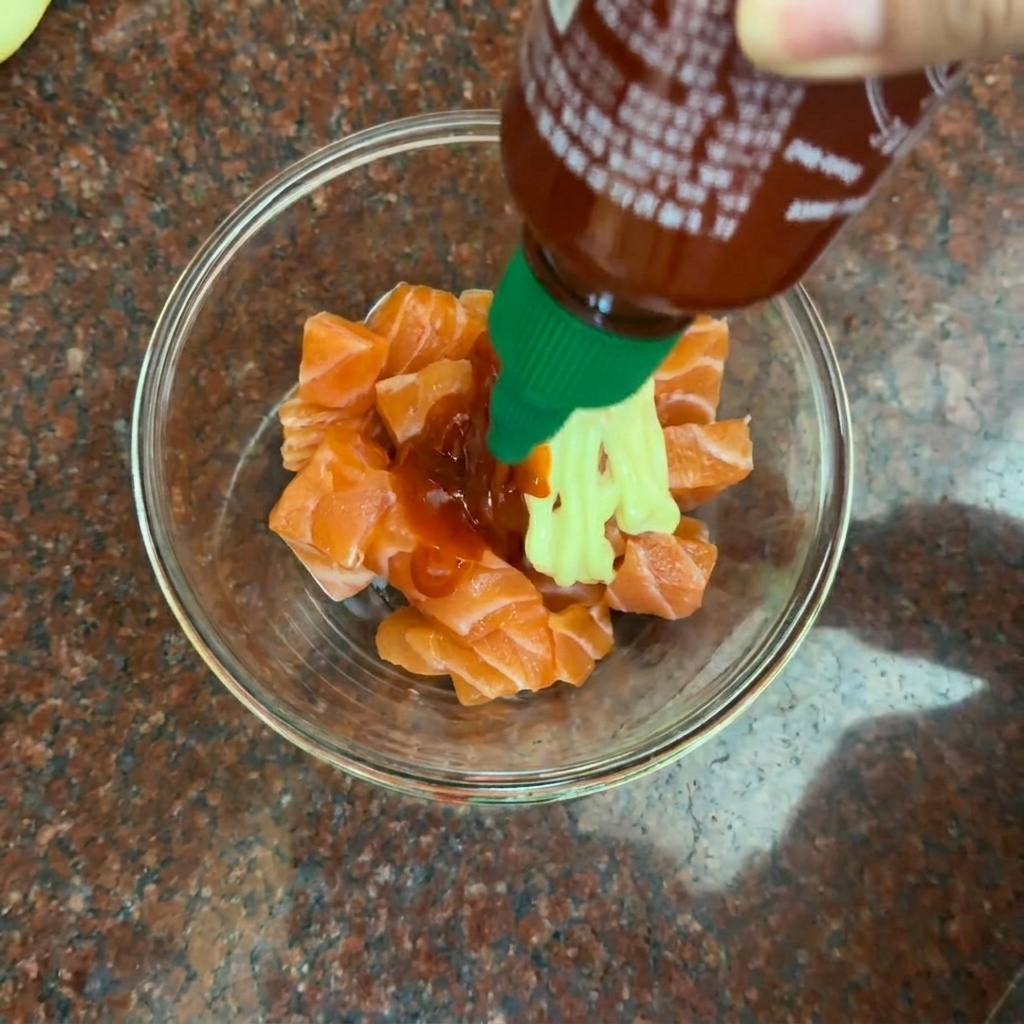 Cubos de salmón fresco en un bol de vidrio listos para ser mezclados con el aderezo picante.
