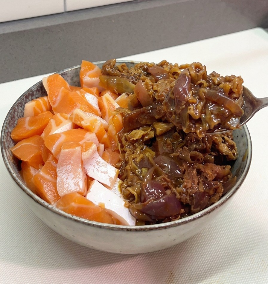 Una cuchara metálica sirviendo una porción de ternera salteada con salsa y cebolla morada en un tazón que ya contiene salmón fresco.