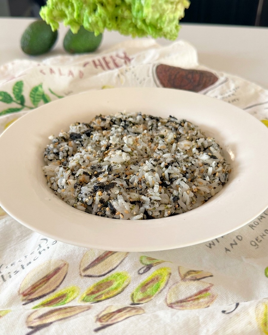 Un tazón blanco con arroz cubierto de forma homogénea con sésamo blanco y negro y copos de alga nori.