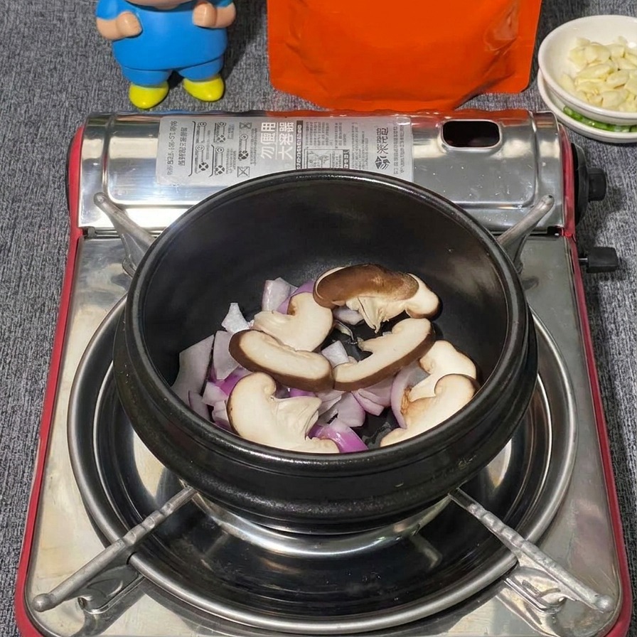 Una variedad de hongos que incluye shiitake en rodajas y ramilletes de hongos shimeji blancos acomodados sobre cebolla roja en una olla de piedra negra.