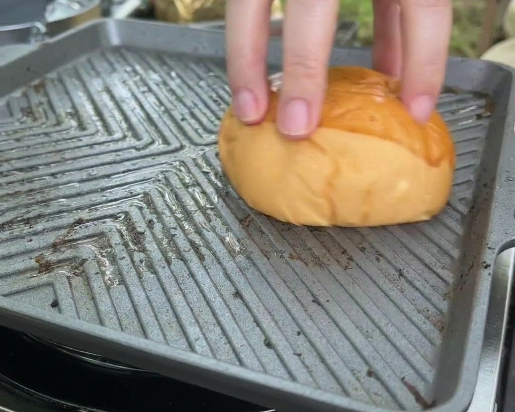 Un pan brioche presionado boca abajo sobre una plancha cuadrada y caliente para tostar su interior.