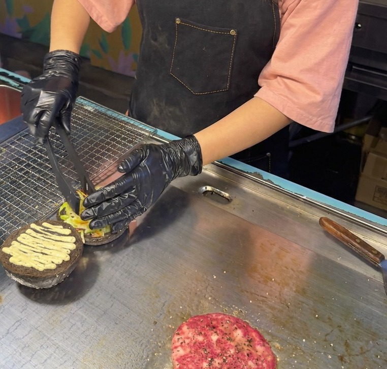 Pinzas colocando una mezcla de lechuga y col lombarda sobre el pan negro con salsa de trufa.