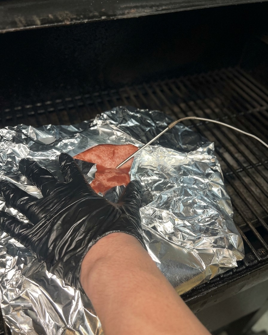 Una sonda de temperatura siendo introducida a través del papel de aluminio en un brisket cocido para verificar la ternura y la temperatura.