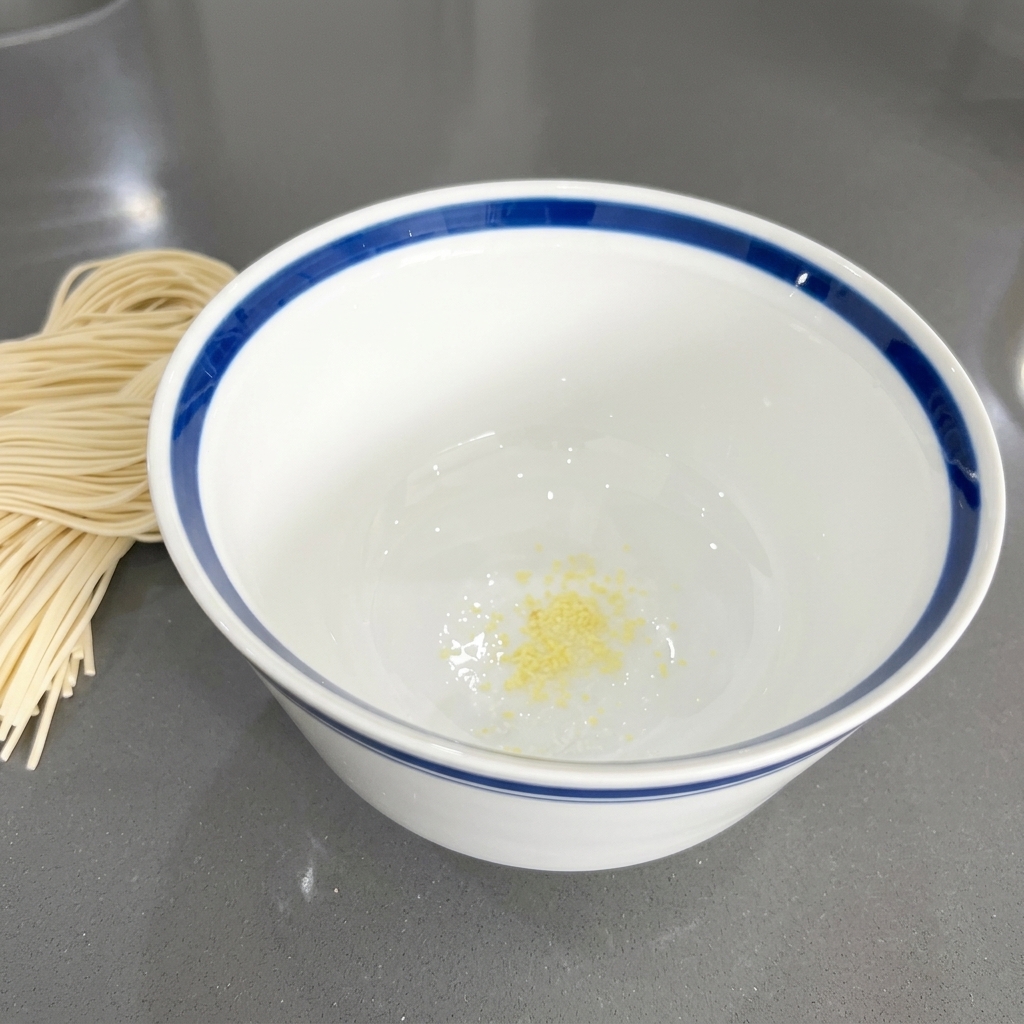 Ajo crudo finamente picado en el fondo de un cuenco de cerámica blanca.