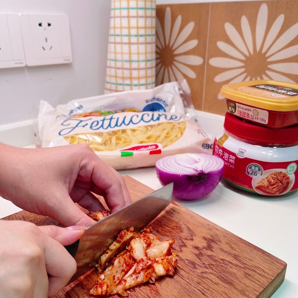 Un cuchillo cortando a través de un montón de kimchi de col sobre una tabla de cortar de madera.