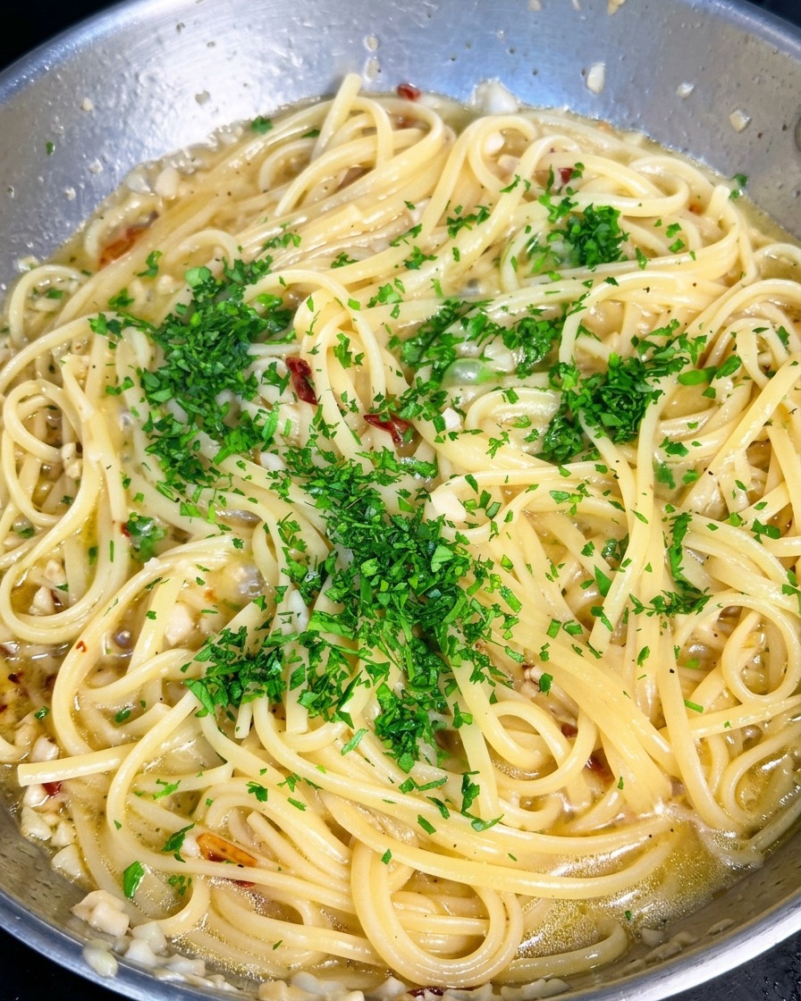 Perejil picado de color verde brillante esparcido sobre una sartén de pasta con ajo y aceite de oliva.