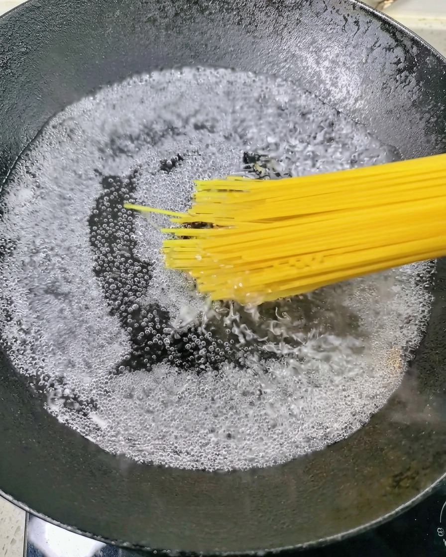 Espaguetis secos introduciéndose en una olla de agua hirviendo.