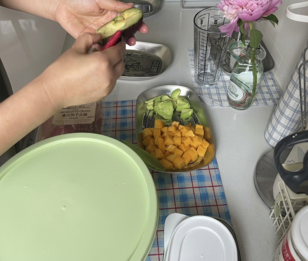 Manos girando un aguacate maduro de piel oscura para abrirlo a la mitad.