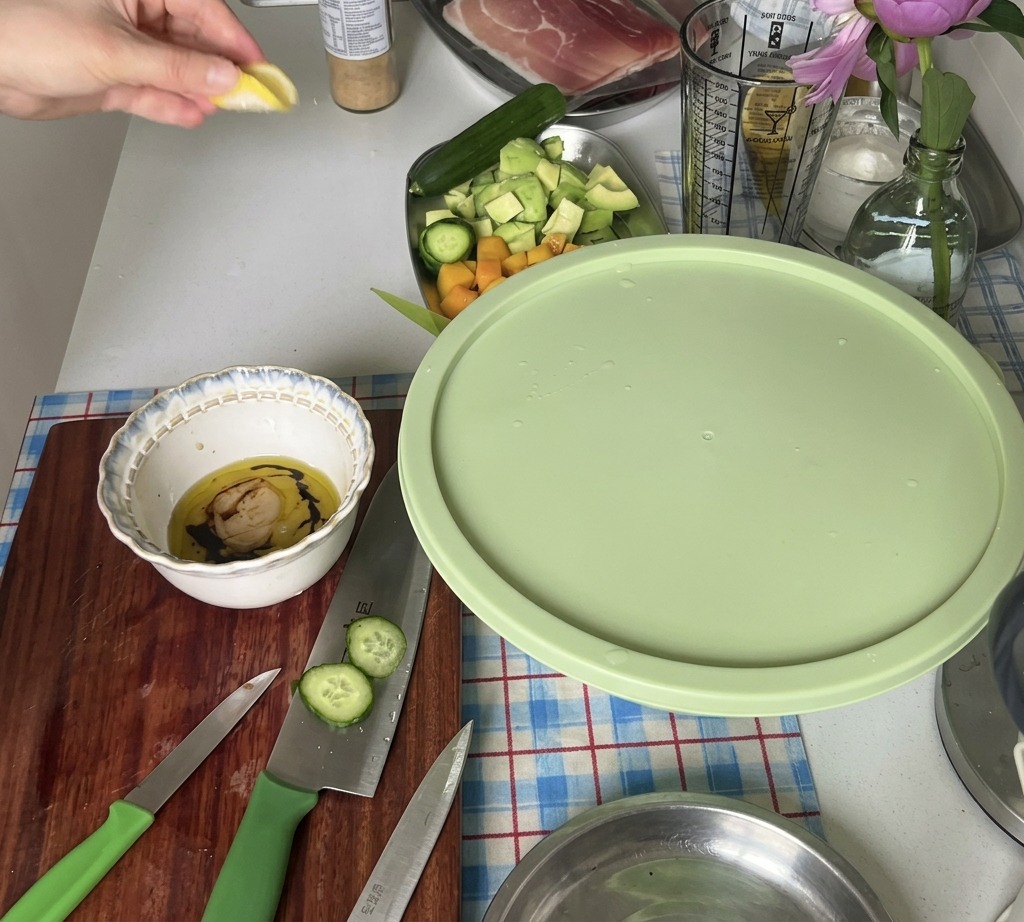 Una mano exprimiendo el jugo de un trozo de limón fresco en un tazón con los ingredientes del aderezo.
