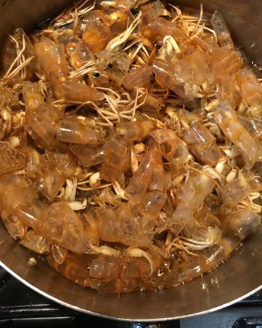 Cáscaras de gamba hirviendo en una mezcla de salsa oscura dentro de una olla.