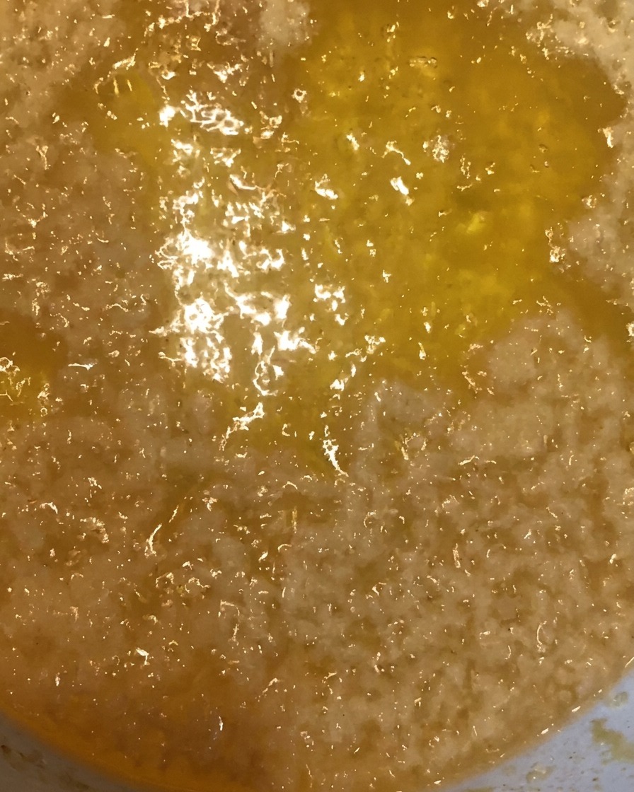 Migas de masa crujiente doradas siendo retiradas del aceite con un colador de metal.