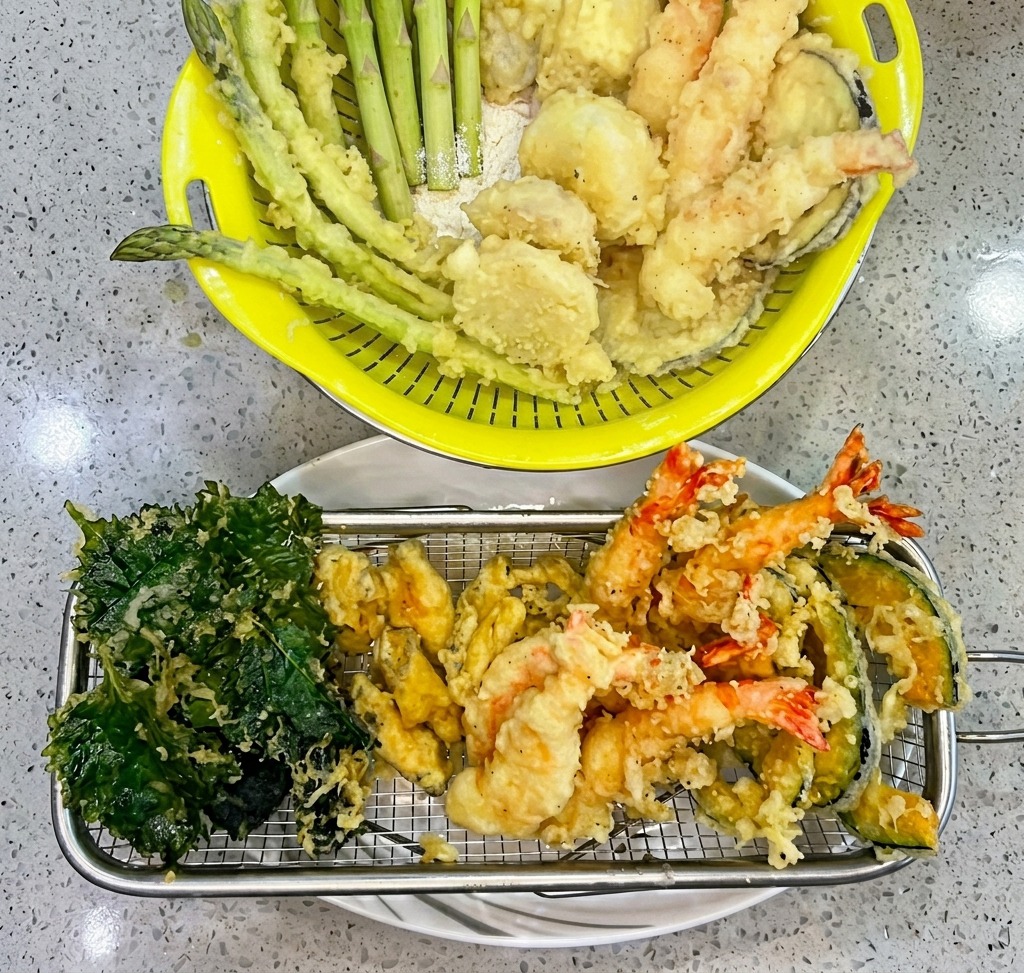 Camarones cubiertos en masa siendo introducidos en aceite caliente dentro de una cesta de freír.