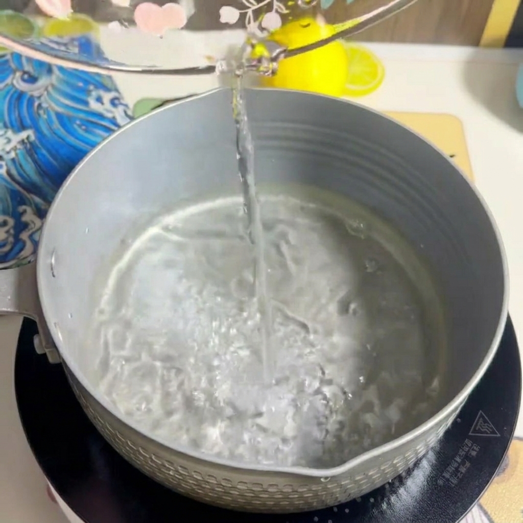 Leche siendo vertida en la olla, mezclándose con el agua.