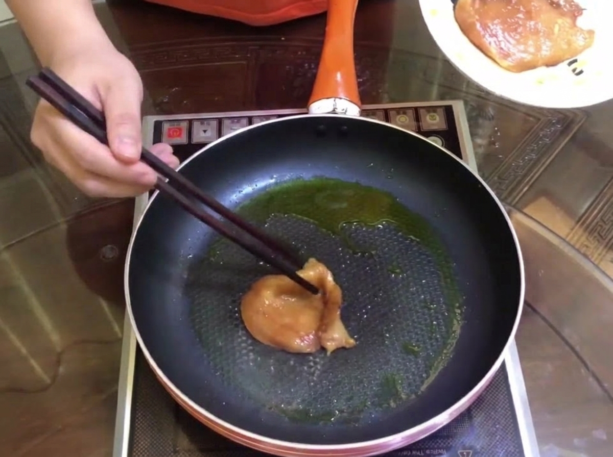 Trozos de carne marinada dorándose en una sartén con un poco de aceite.