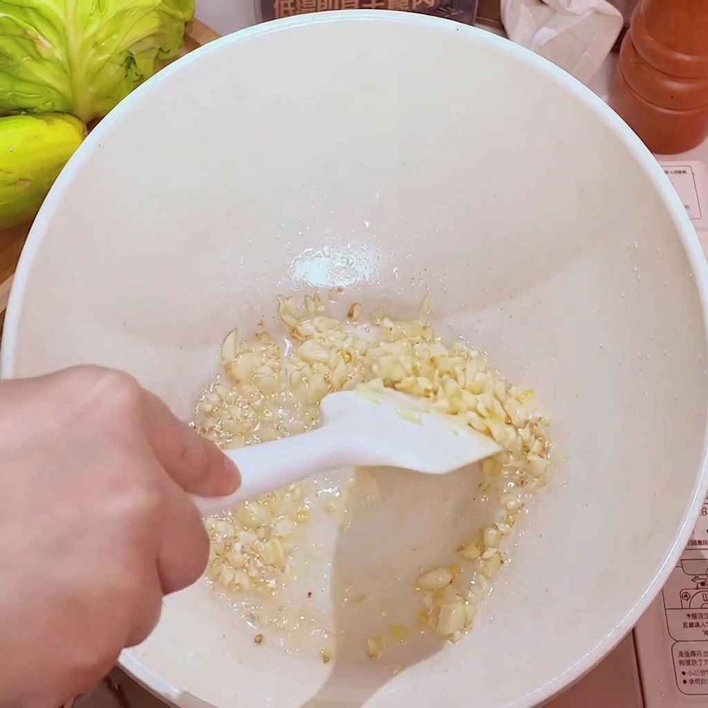 Ajo picado chisporroteando en una sartén con aceite, volviéndose dorado y aromático.