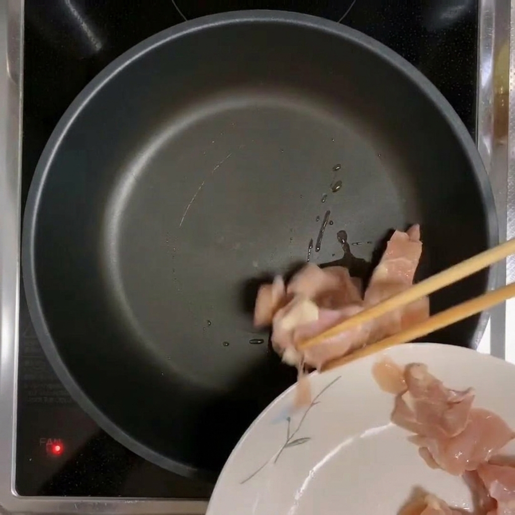 Trozos de pollo colocados en una sartén precalentada y aceitada.