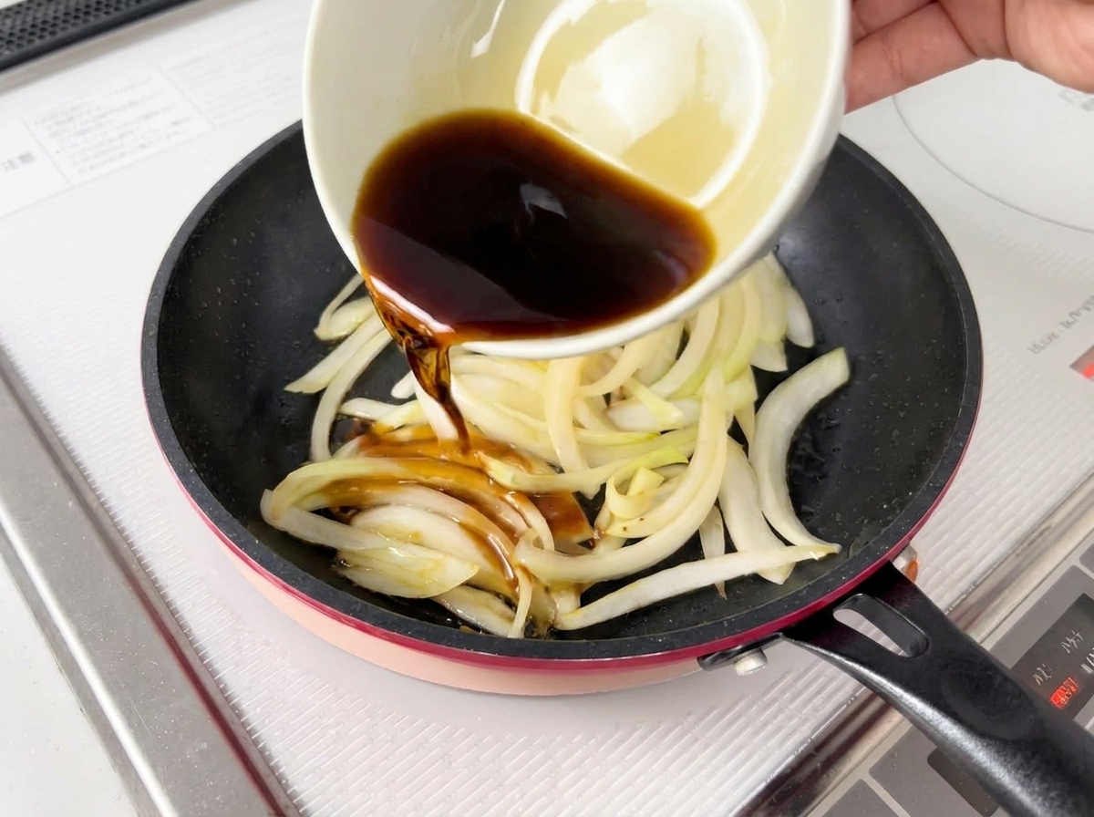 Salsa oscura siendo vertida desde un cuenco sobre las cebollas cocinadas.