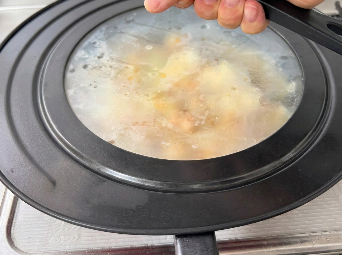 Tapa puesta sobre la sartén, con vapor visible en su interior.