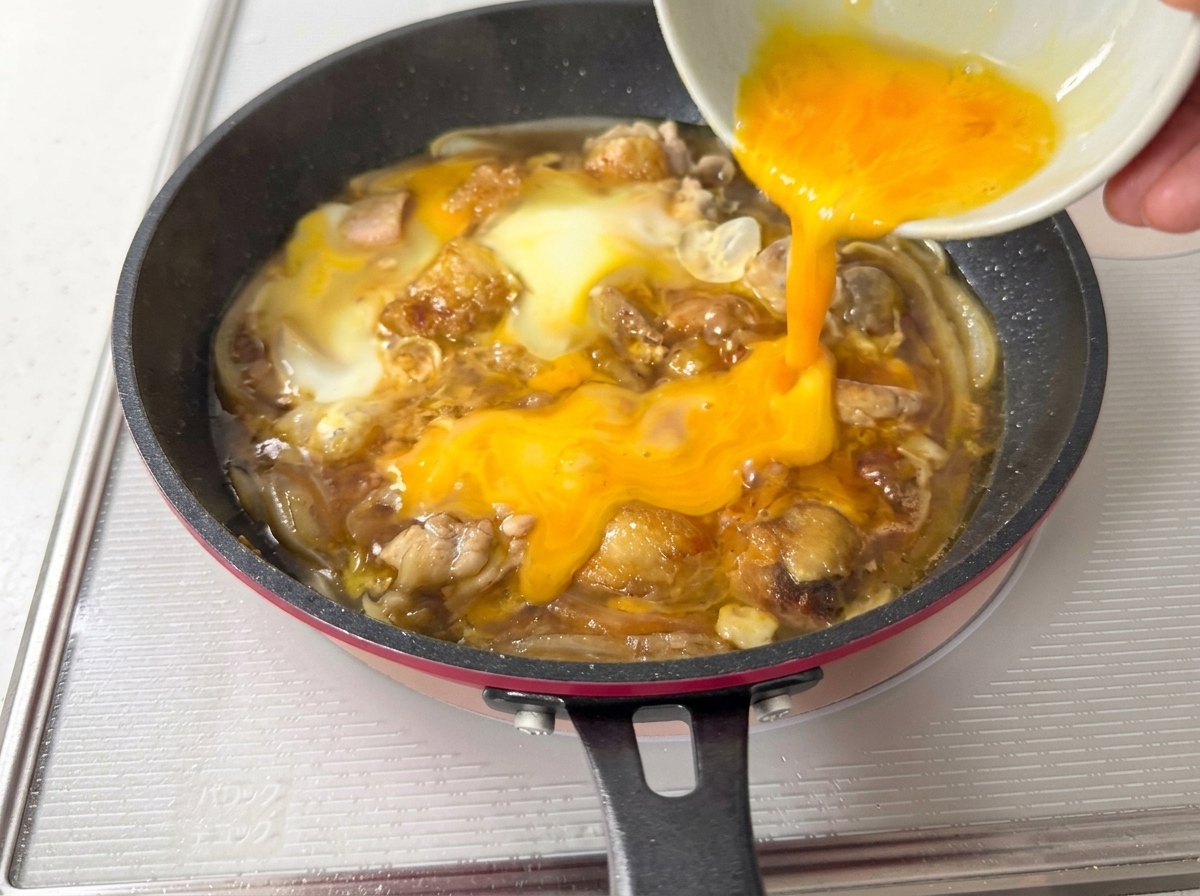 El resto de los huevos vertiéndose sobre los ingredientes parcialmente cocidos.