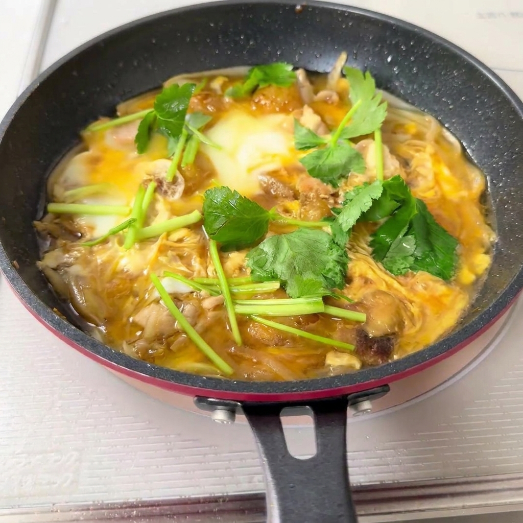 Mezcla de Oyakodon siendo vertida sobre un tazón de arroz blanco caliente.