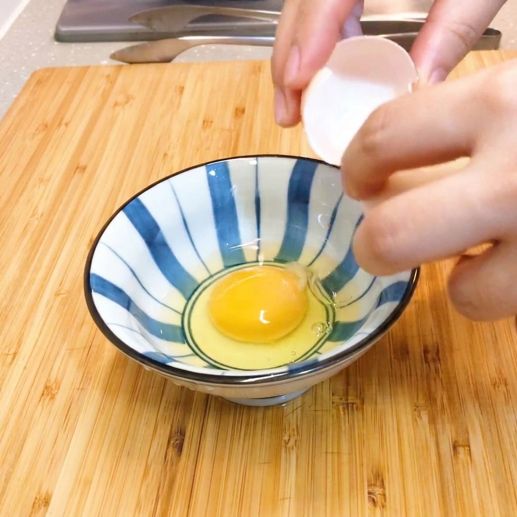Dos huevos crudos siendo batidos suavemente con palillos en un bol de cerámica a rayas azules y blancas.
