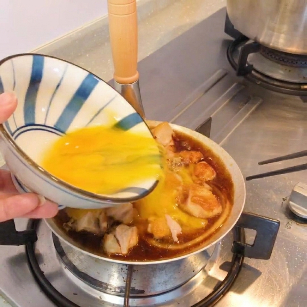 Un plato terminado estilo Oyakodon en una sartén, adornado con cebolleta fresca.