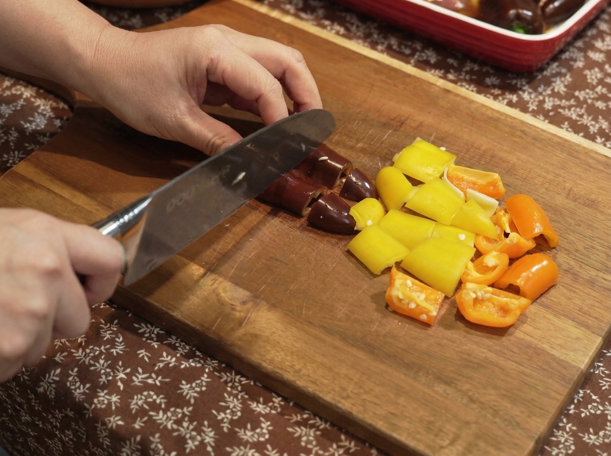 Pimientos y cebollas cortados en trozos pequeños sobre una tabla de madera.