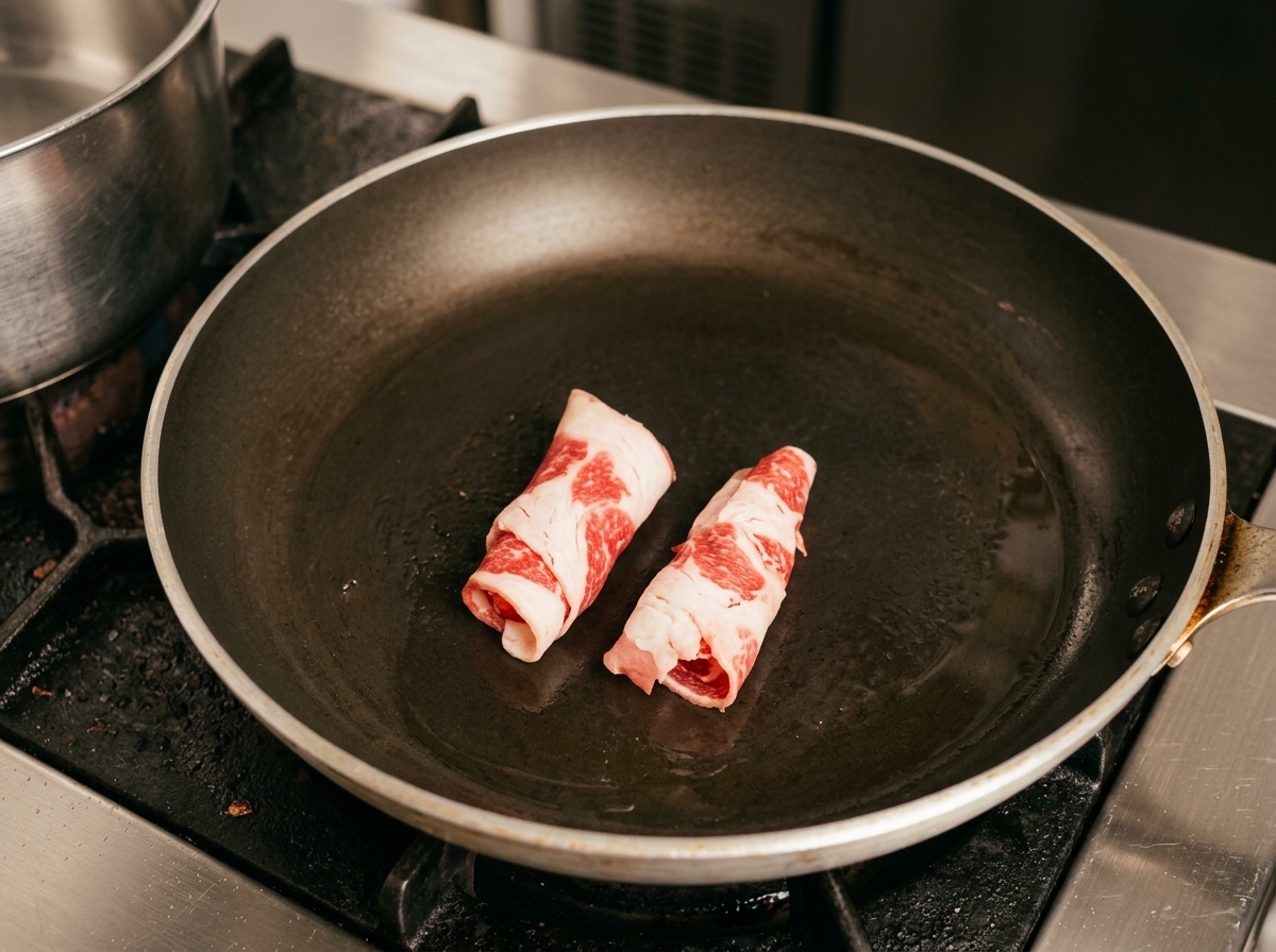 Friendo rollos de carne de ternera cruda en la sartén caliente.