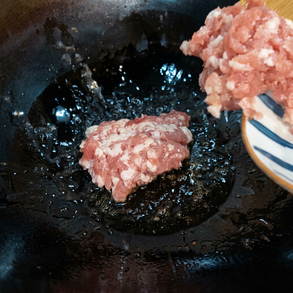 Carne picada salteándose en un wok caliente a fuego medio-bajo hasta que se dore.