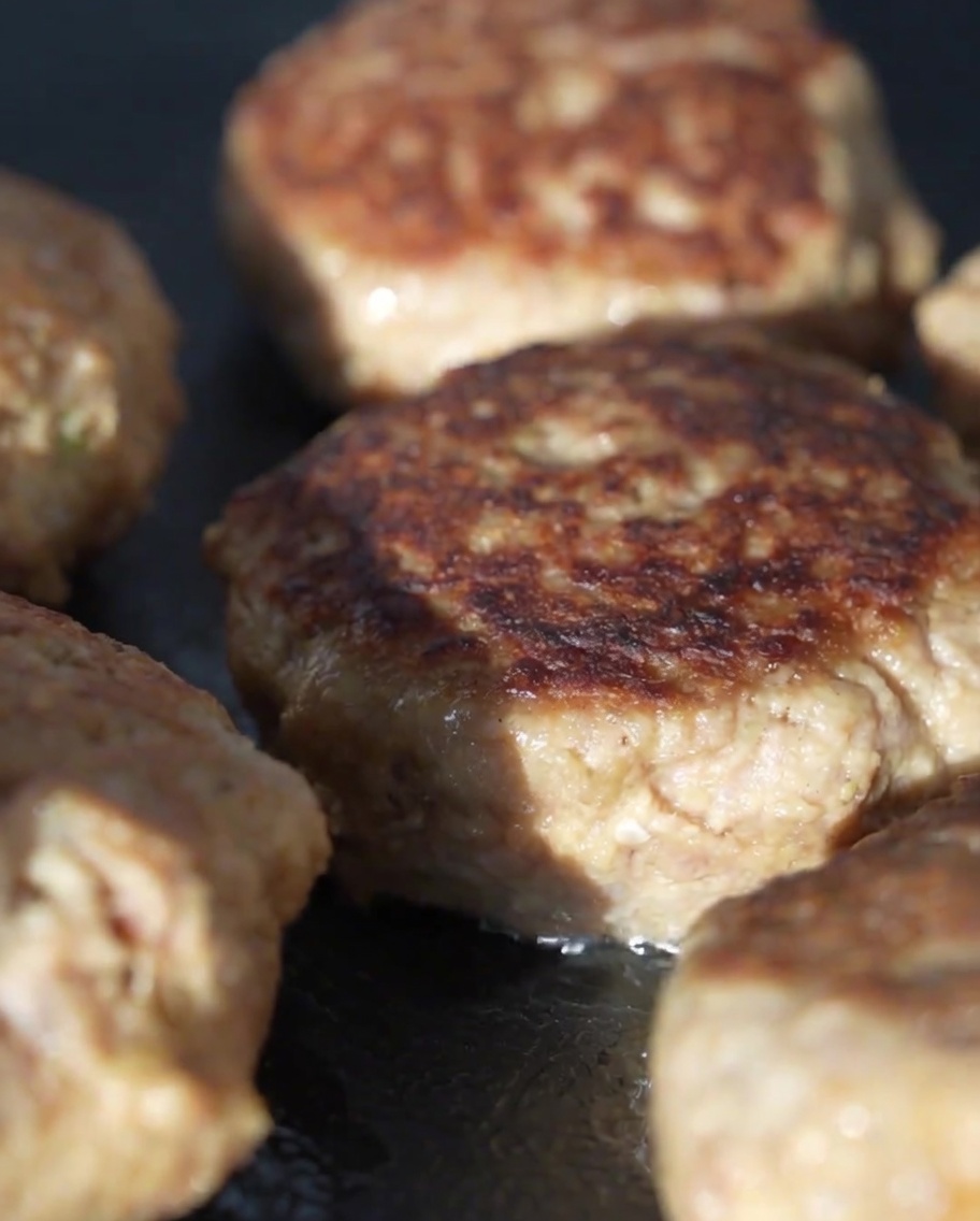 Tapa de vidrio cubriendo la sartén con hamburguesas de carne dentro para cocinarlas al vapor.