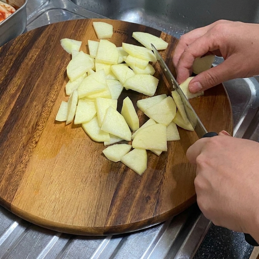 Una cebolla cortada en gajos gruesos sobre una tabla de cortar de madera.