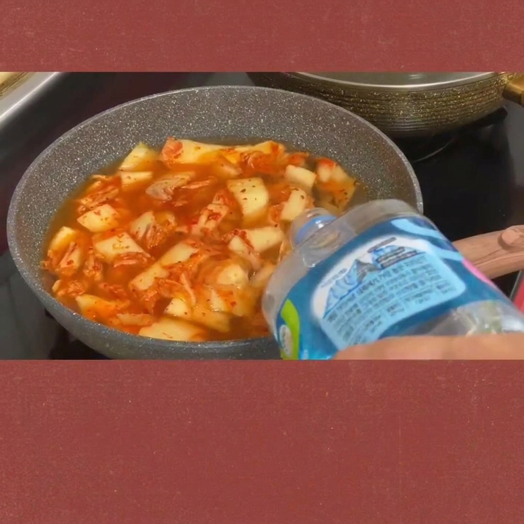 Rodajas de spam siendo añadidas al estofado de kimchi burbujeante.