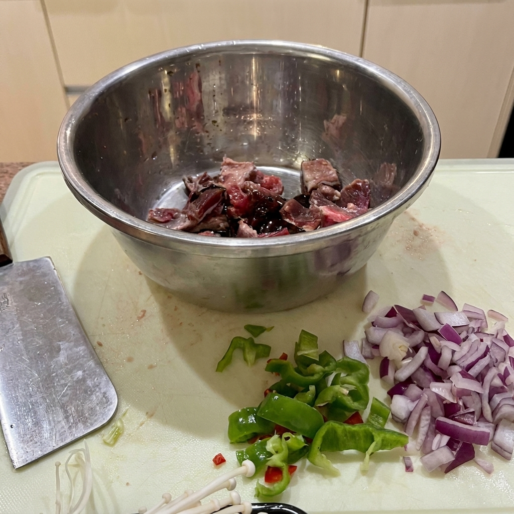 Trozos de ternera marinándose en un bol de acero inoxidable con salsa de soja, salsa de ostras y almidón.