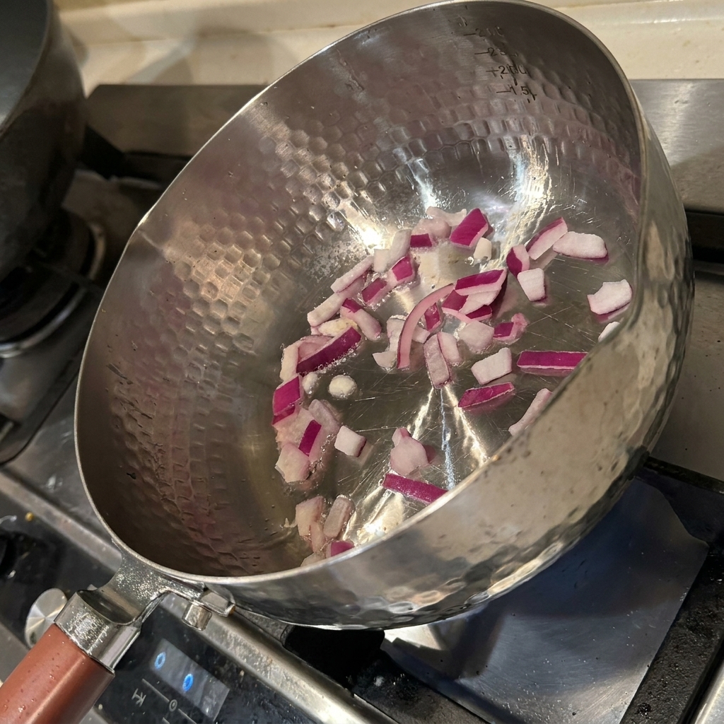 Cubos de cebolla chisporroteando en una sartén caliente con aceite, volviéndose fragantes y tiernos.