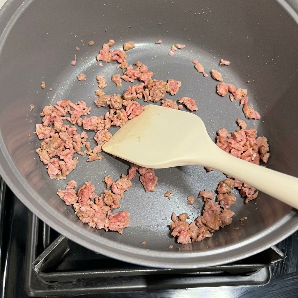 Kimchi y Spam dorado siendo salteados juntos en una olla.