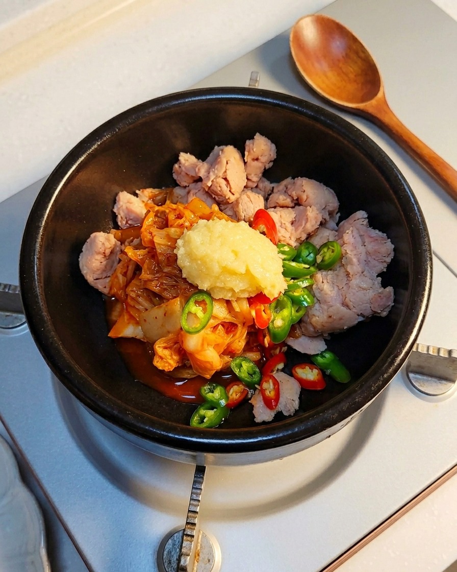 Una cucharada de ajo picado siendo añadida a los ingredientes en la olla de piedra.