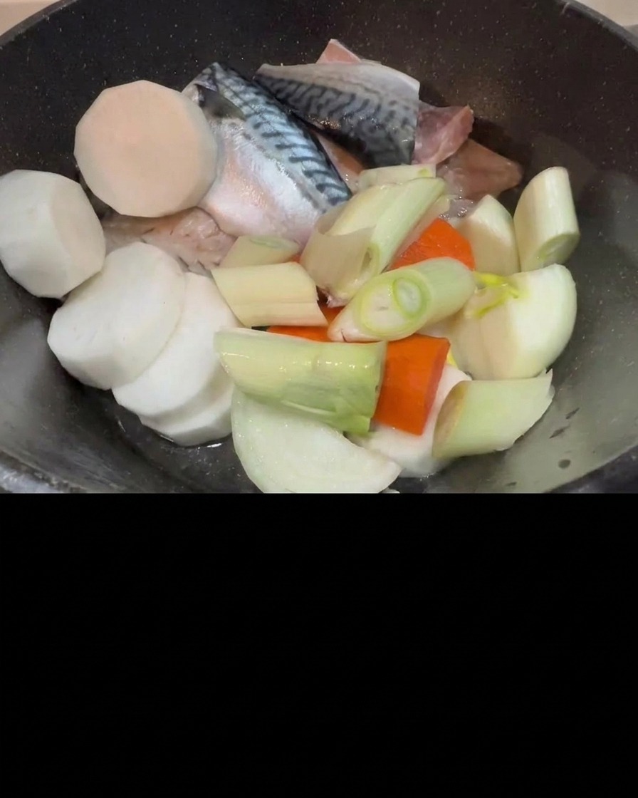 Kimchi añadiéndose a la olla con la caballa cruda, el rábano y la cebolleta.