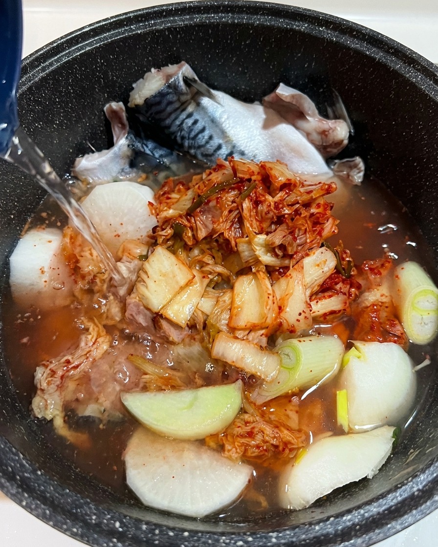 Primer plano de condimento líquido añadiéndose a la olla, con los ingredientes claramente visibles bajo el agua.