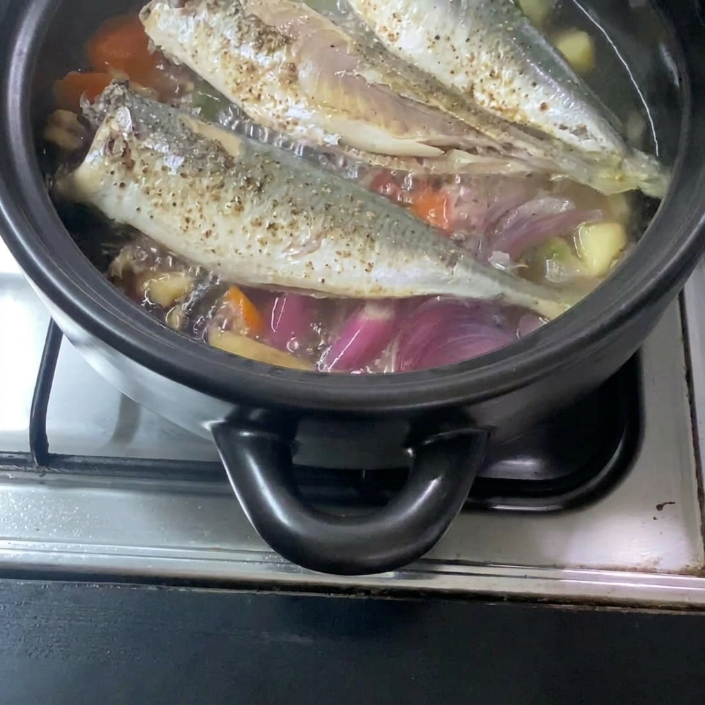 La mezcla de miso líquido vertida en la olla, integrándose con la caballa cocida y las verduras.