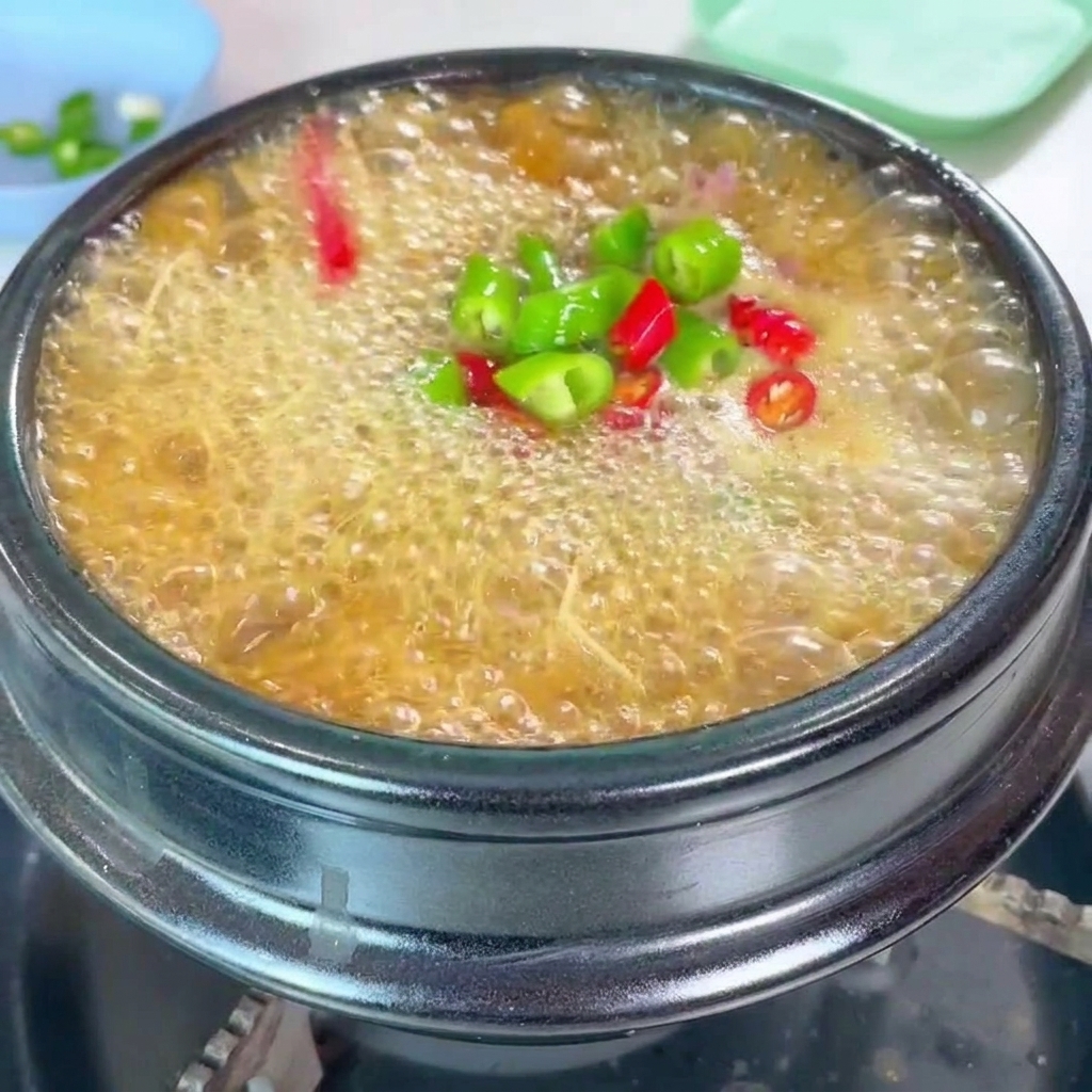 Una vibrante cobertura de chiles verdes y rojos picados y cebollino fresco añadidos al estofado a fuego lento.
