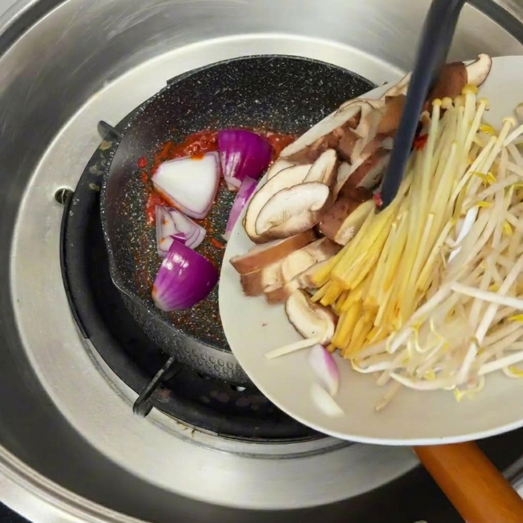 Aceite de sésamo vertido con una cuchara sobre un estofado de ternera y tofu.